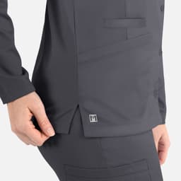A dark grey women's jacket with a round neck and snap buttons, featuring a side pocket and a small logo.
