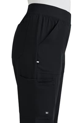 A side view of black boot cut pants featuring pockets and an elastic waistband, with a logo on the leg.