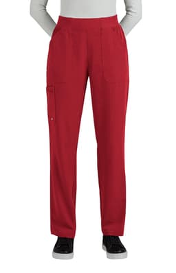 A pair of red boot cut pants features multiple pockets and a comfortable waistband. The model stands with hands in pockets.