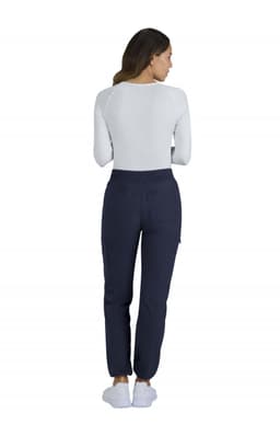 A woman is wearing navy Harper pants and a white long-sleeve top, viewed from the back. The pants have a logo.