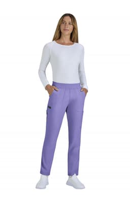 A woman is wearing limited edition purple Harper pants with pockets, paired with a white long-sleeve top and white shoes.