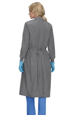 A clinical cover gown in grey, featuring a back tie and long sleeves, worn by a person with blue gloves.