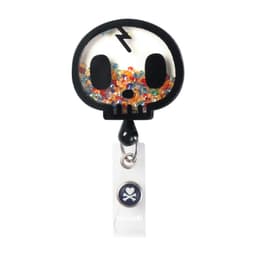 A black shaker badge featuring a skull design filled with colourful glitter and a small branding logo.