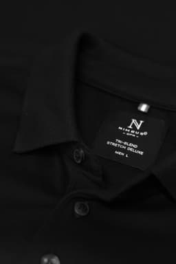 A black polo shirt with a collar and buttons, featuring a label with sizing information.