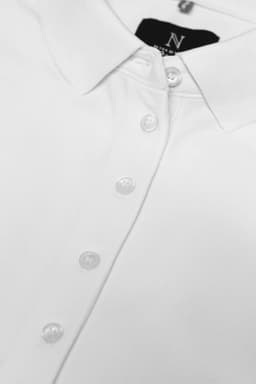 A white women's polo shirt featuring a collar and button placket, with a logo on the collar.
