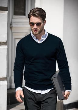 A navy V-neck jumper paired with a white shirt and sunglasses, held by a man carrying a folder.