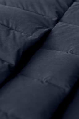 A close-up of a navy blue down jacket, featuring quilted panels and a soft texture. The image displays the jacket's padding.