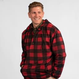 A red and black checkered 1/4 zip polar fleece hoodie worn by a smiling man. Features a front pocket and a logo.