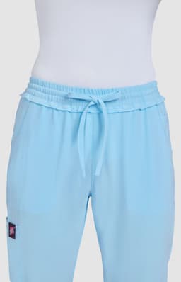 Light blue pants with a relaxed fit and drawstring waistband, featuring a logo on one side.