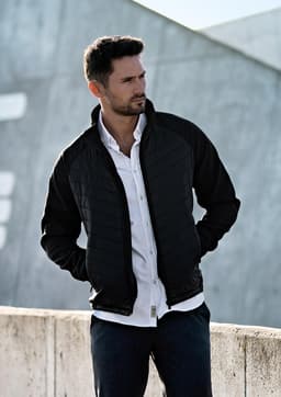 A soft shell jacket in black, featuring a zip front and a modern design, displayed on a man outdoors.