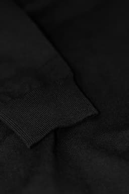 A close-up of a black Brighton Cardigan featuring a ribbed cuff detail. The fabric appears soft and textured.