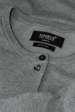 A grey cardigan with a round neckline and button details, featuring a label with branding.