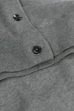 A grey cardigan featuring a buttoned collar and ribbed detailing. It has a branding logo on the fabric.