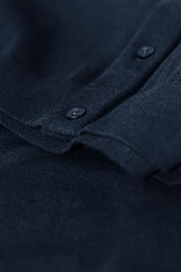 A navy blue cardigan featuring a button-up front and textured knit fabric. It has a subtle branding logo visible.