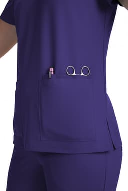 A purple medical scrub top features a pocket holding a pen and scissors, showcasing a practical design.