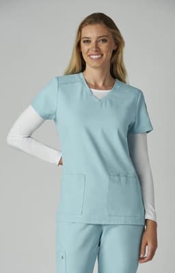 A scrubs top in light blue, featuring a V-neck and two front pockets, worn by a smiling model.
