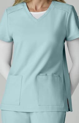 A scrub top in light blue, featuring a V-neck, short sleeves, and two front pockets. It has a logo on the sleeve.