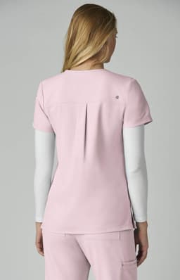 A pink top with short sleeves and a back pleat, featuring a logo on the back.