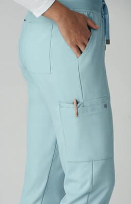 Atria Pant in light blue with pockets, showcasing a side view and a logo on the fabric.