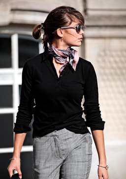 A black women's polo shirt styled with a scarf, worn by a woman outdoors.