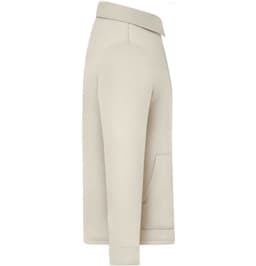 A beige unisex shirt jacket featuring a collar, side pocket, and a relaxed fit. It has a logo patch.