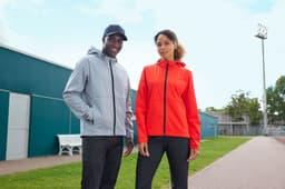 A grey softshell jacket and a red softshell jacket worn by models outdoors, both featuring logos.