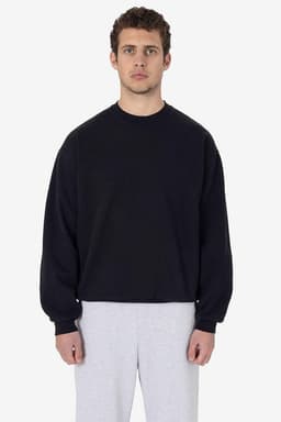 A black heavy fleece pullover sweater worn by a model, paired with light grey bottoms. It features a logo.