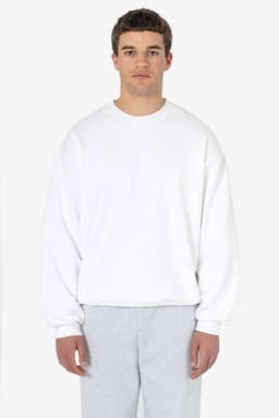A heavy fleece pullover in white, featuring long sleeves and a relaxed fit. The model is wearing grey pants.