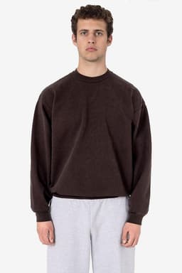 A brown heavy fleece pullover with long sleeves, worn by a model, paired with light grey pants.