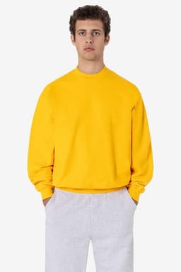 A yellow heavy fleece pullover displayed on a model, paired with grey trousers. The pullover features a logo.