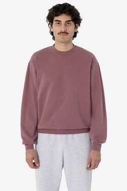 A mauve garment dye heavy fleece pullover with long sleeves, displayed on a model wearing grey pants.