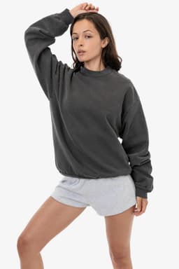 A woman poses wearing a grey heavy fleece pullover and light grey shorts, showcasing a casual style.