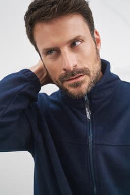 A man wearing a navy blue full-zip polar fleece jacket, featuring a collar and a branding logo.