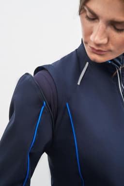 A navy softshell jacket with blue accents, featuring a zip-off design. It has a sleek, modern fit and a logo.