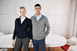 A navy and a grey zip-cardigan on two models standing in a modern indoor setting.