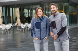 A grey polar fleece jacket featuring black and blue accents, worn by a man and woman in an outdoor setting.