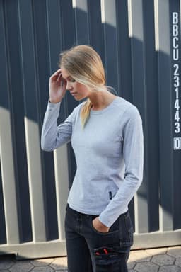 A grey long-sleeve t-shirt displayed on a model against a striped background, featuring a logo.