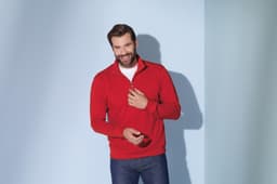 A red Round-Neck Zip jumper with a zippered collar, worn by a smiling man against a blue background.