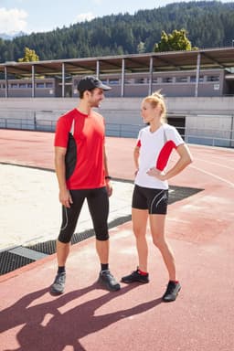 A red and white Ladies Running-T featured on a woman and a coordinated outfit on a man, both set on an athletic track.