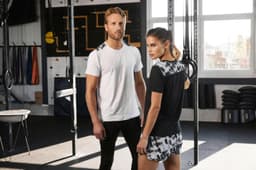 A ladies' sports shirt in black with a patterned back, worn by a model alongside a man in a white t-shirt.