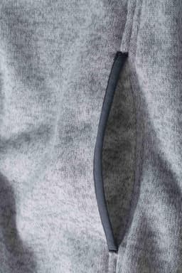 A grey knitted fleece hoodie featuring a stylish side pocket with a contrasting trim.