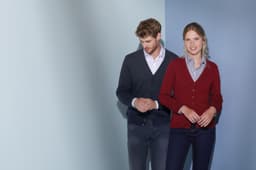 A man in a navy cardigan and a woman in a burgundy cardigan standing against a softly coloured background.