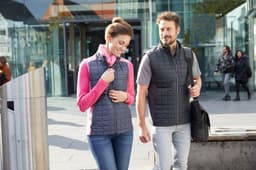A grey knitted hybrid vest worn by two people, one in a pink top, walking in an urban setting.