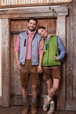 A grey and green ladies knitted fleece vest on a woman, paired with a checked shirt and shorts. Two people stand together.