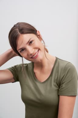 A woman in an olive green t-shirt smiles at the camera. The shirt has a fitted design and a round neckline.