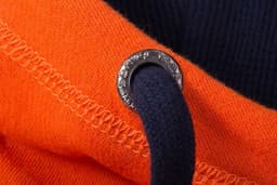 A close-up of an orange zip-hoodie featuring a navy drawstring and a branded metal eyelet.