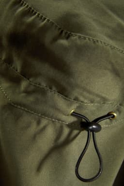 An olive green fabric with a drawstring feature, showcasing a close-up of the material's texture and stitching.