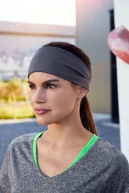 A running headband in grey worn by a woman with long brown hair, paired with a grey athletic top.