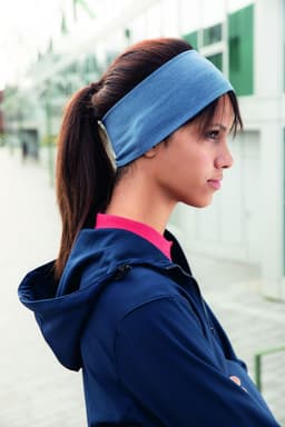 A blue bio cotton headband worn by a woman with long hair, set against an outdoor backdrop.