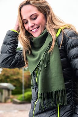 An elegant green scarf draped around a smiling woman, paired with a puffy black jacket.